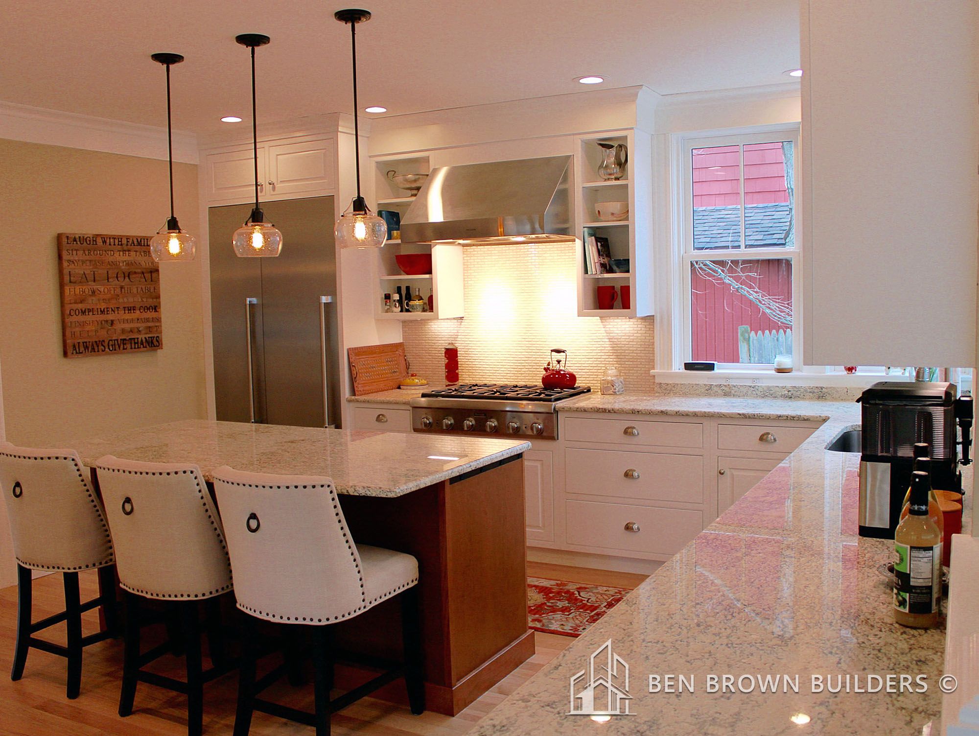 Elegant kitchen with a breakfast bar, chic pendant lighting, and white cabinetry against a red exterior view
