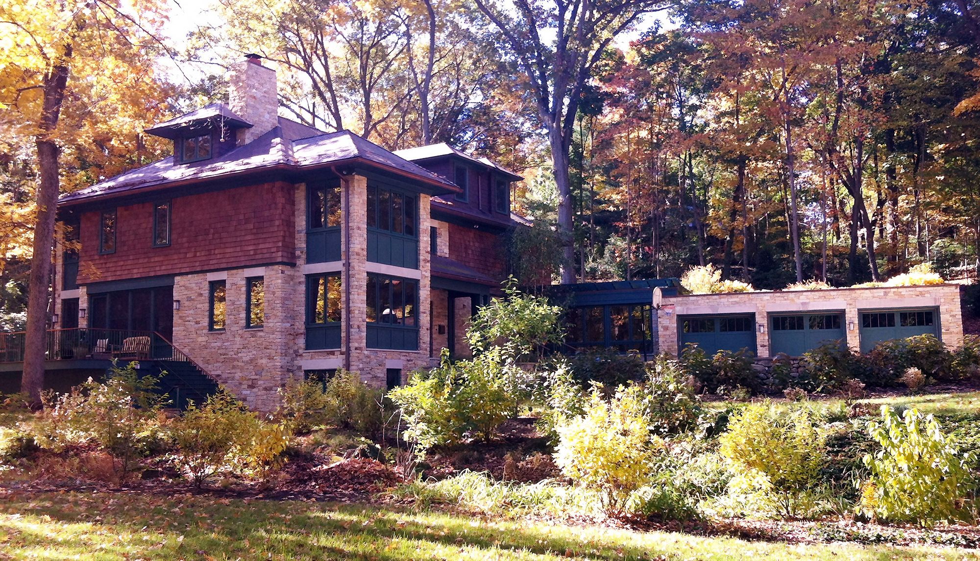 Traditional house with stone accents surrounded by autumn foliage and clear blue skies