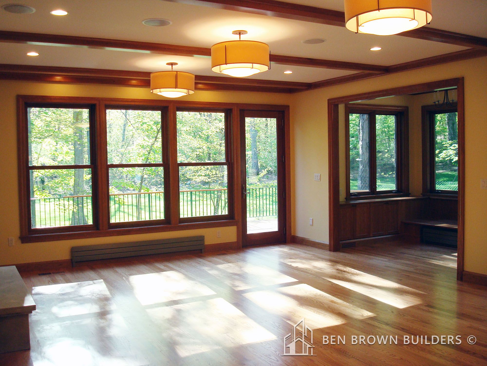 Inviting room with large windows overlooking greenery, wooden trims, and warm pendant lighting