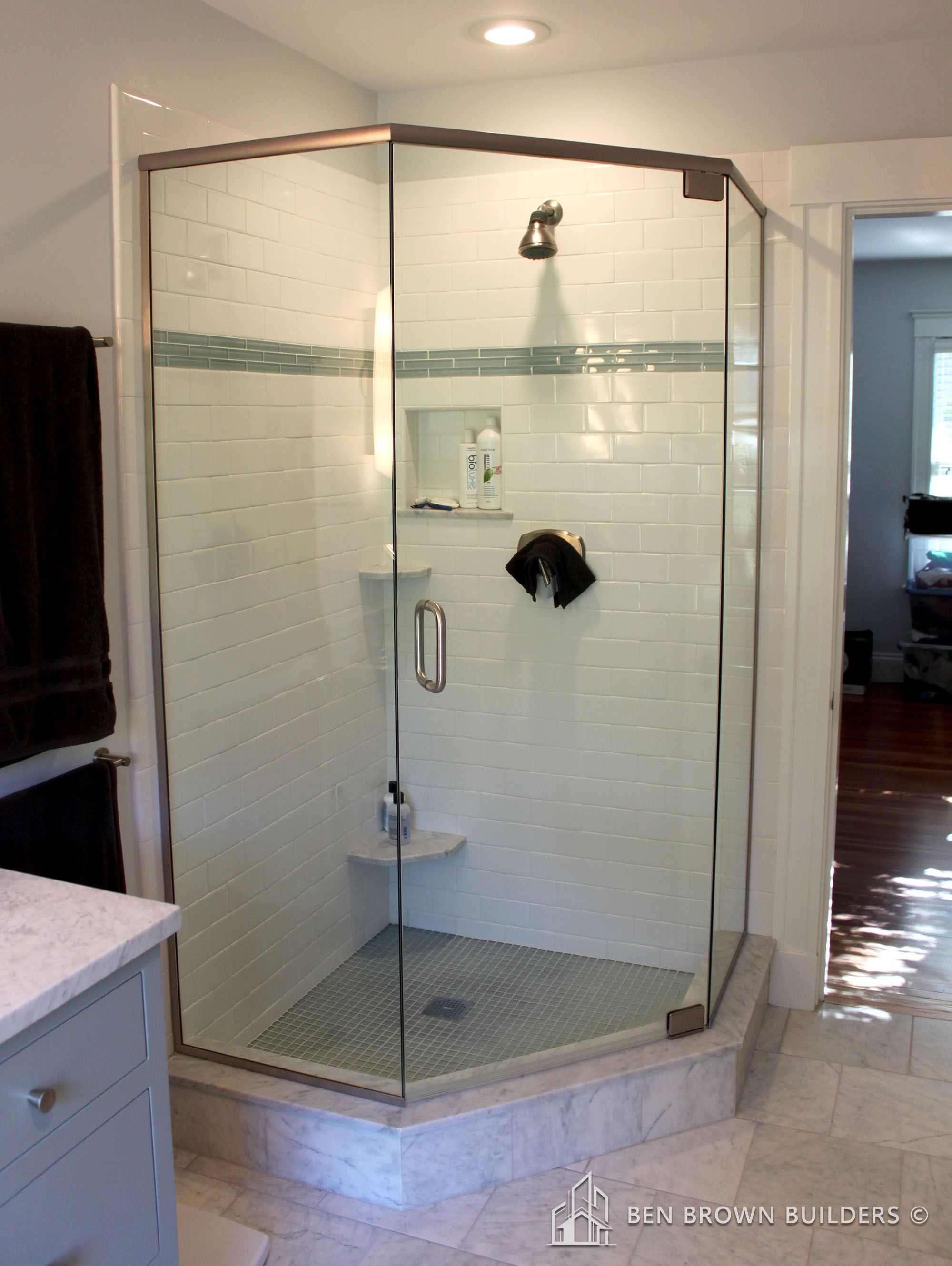 Modern bathroom with a glass-enclosed shower, white subway tiles, and marble flooring