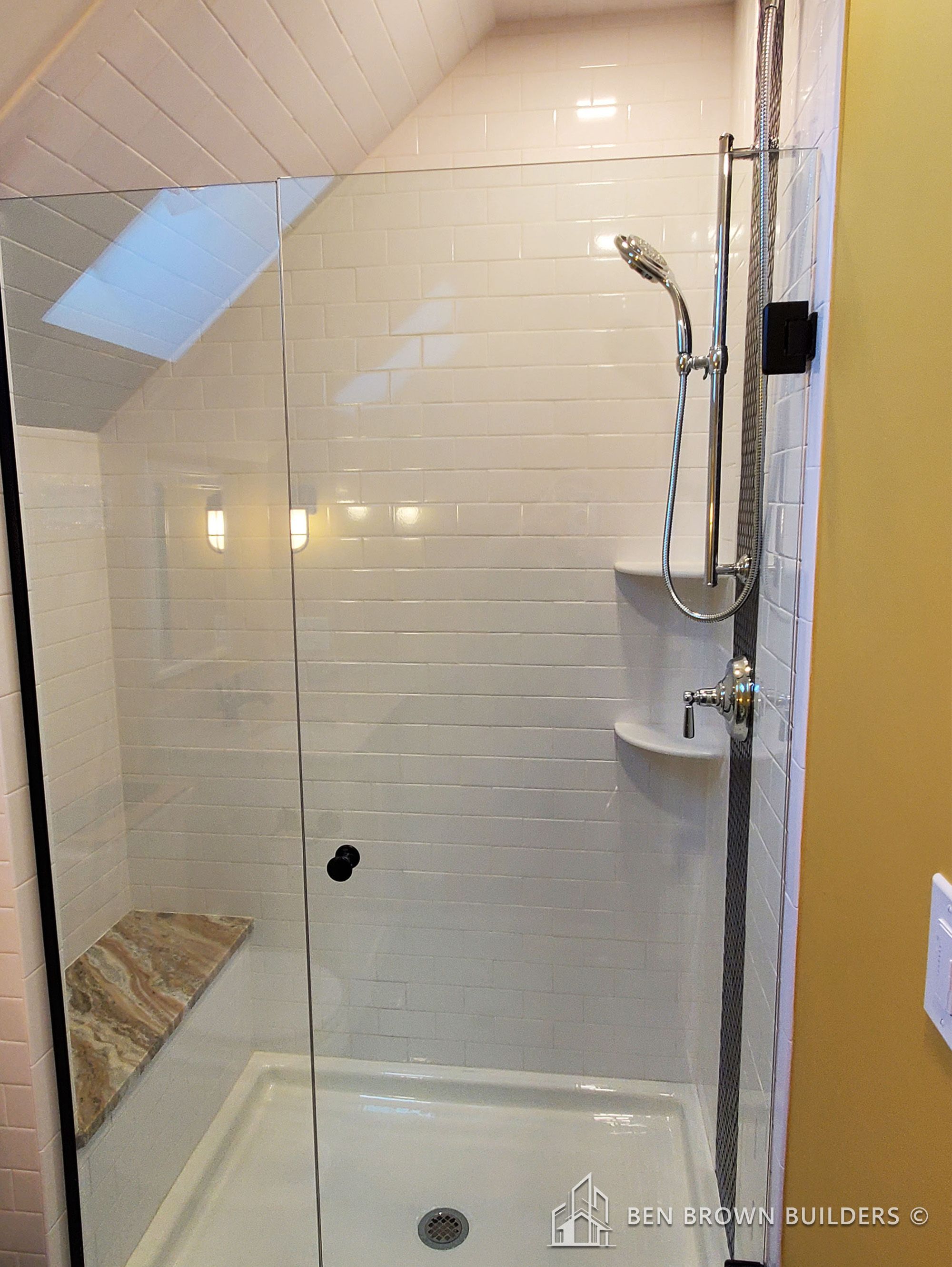 Sleek walk-in shower with white subway tiles, chrome shower system, and a recessed shelf for toiletries