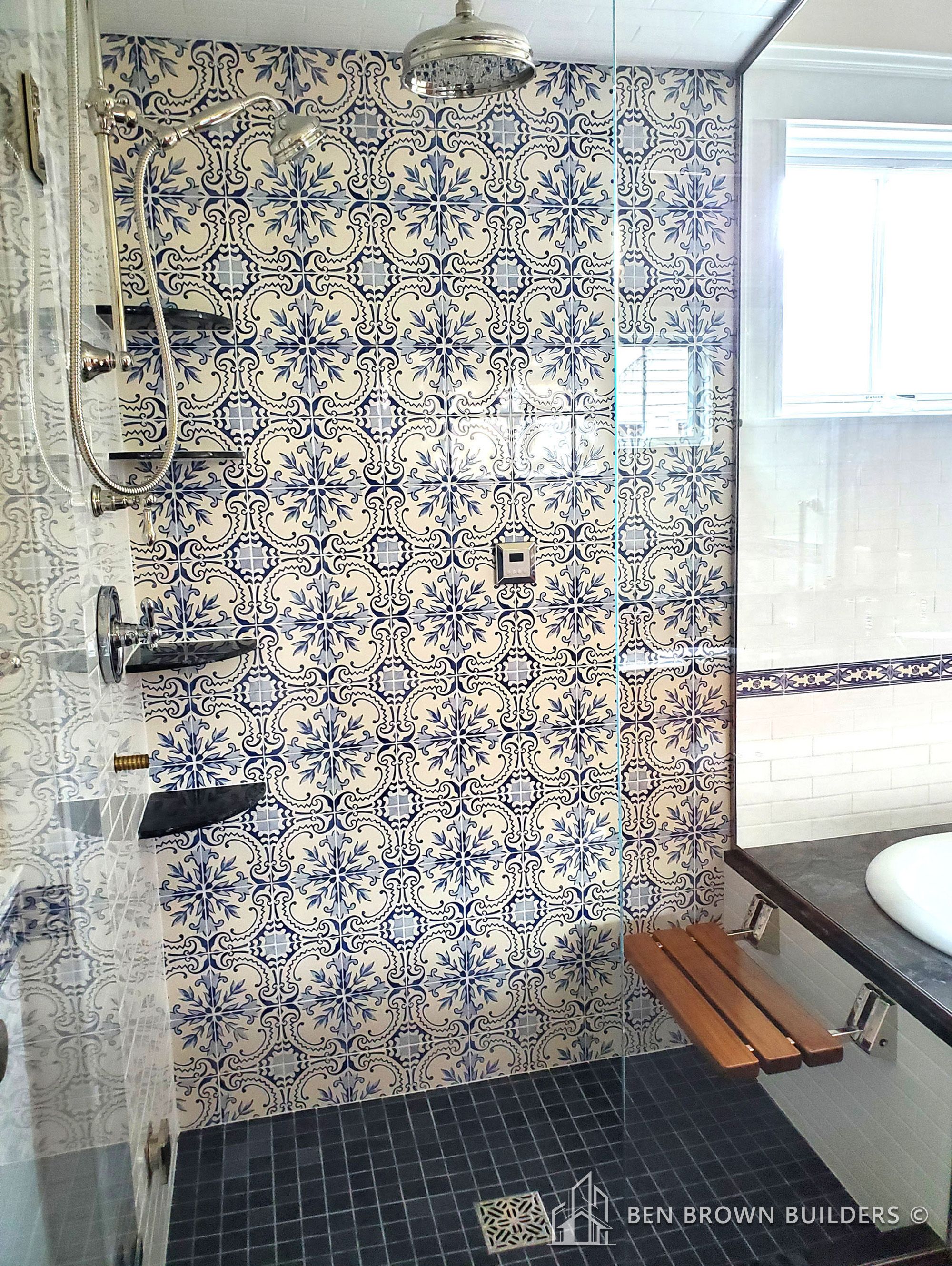 Luxurious bathroom with ornate blue patterned tiles in shower area, sleek glass door, and natural light