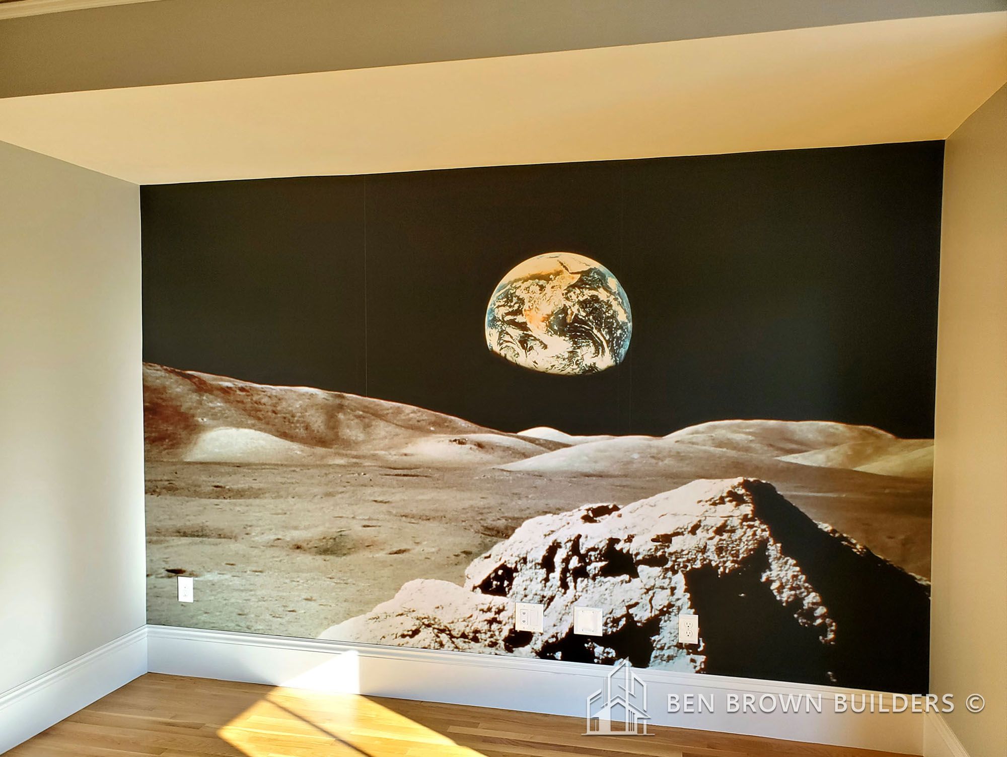 Room with hardwood floor featuring a large wall mural of the Earth as seen from the moon's surface