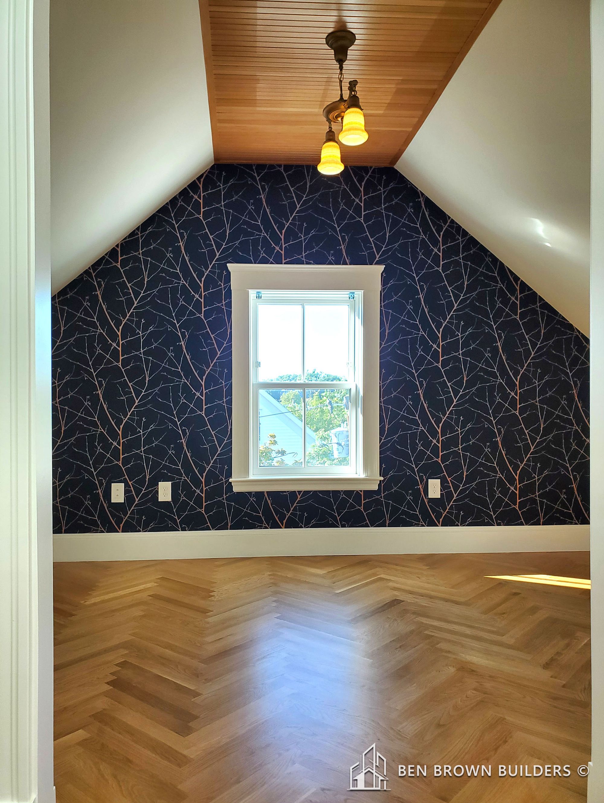 Attic room with chevron hardwood floor, a dark blue wallpaper with golden lines, and a wooden ceiling