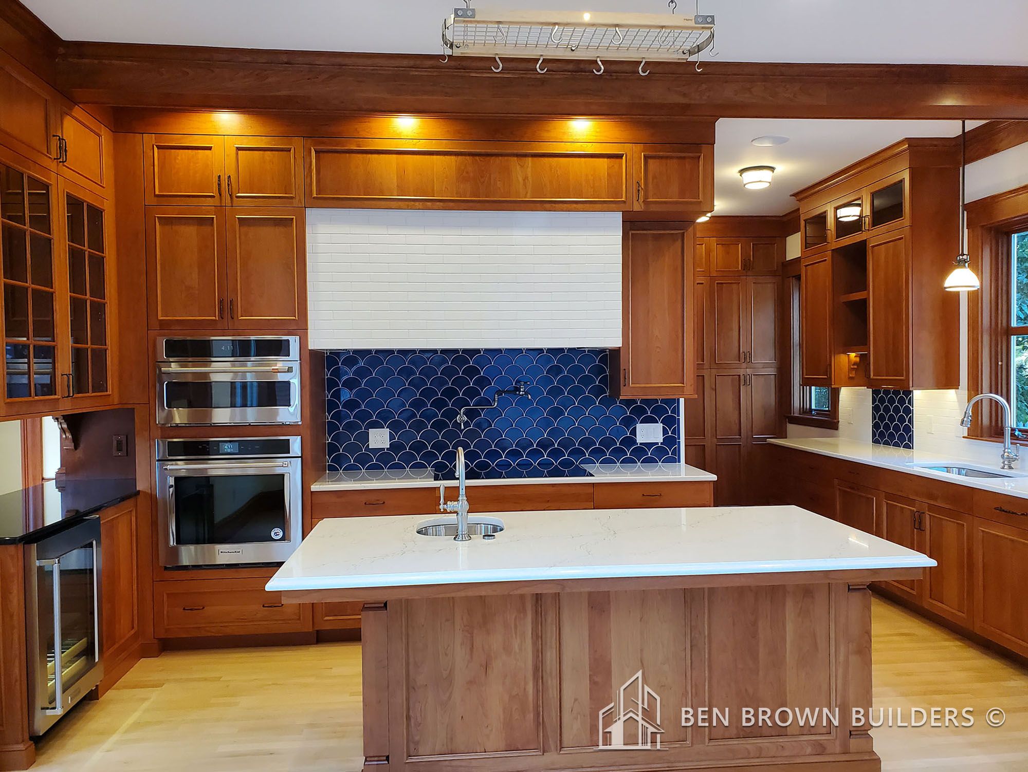 Modern kitchen with wooden cabinetry, stainless steel appliances, and a central island with a sink