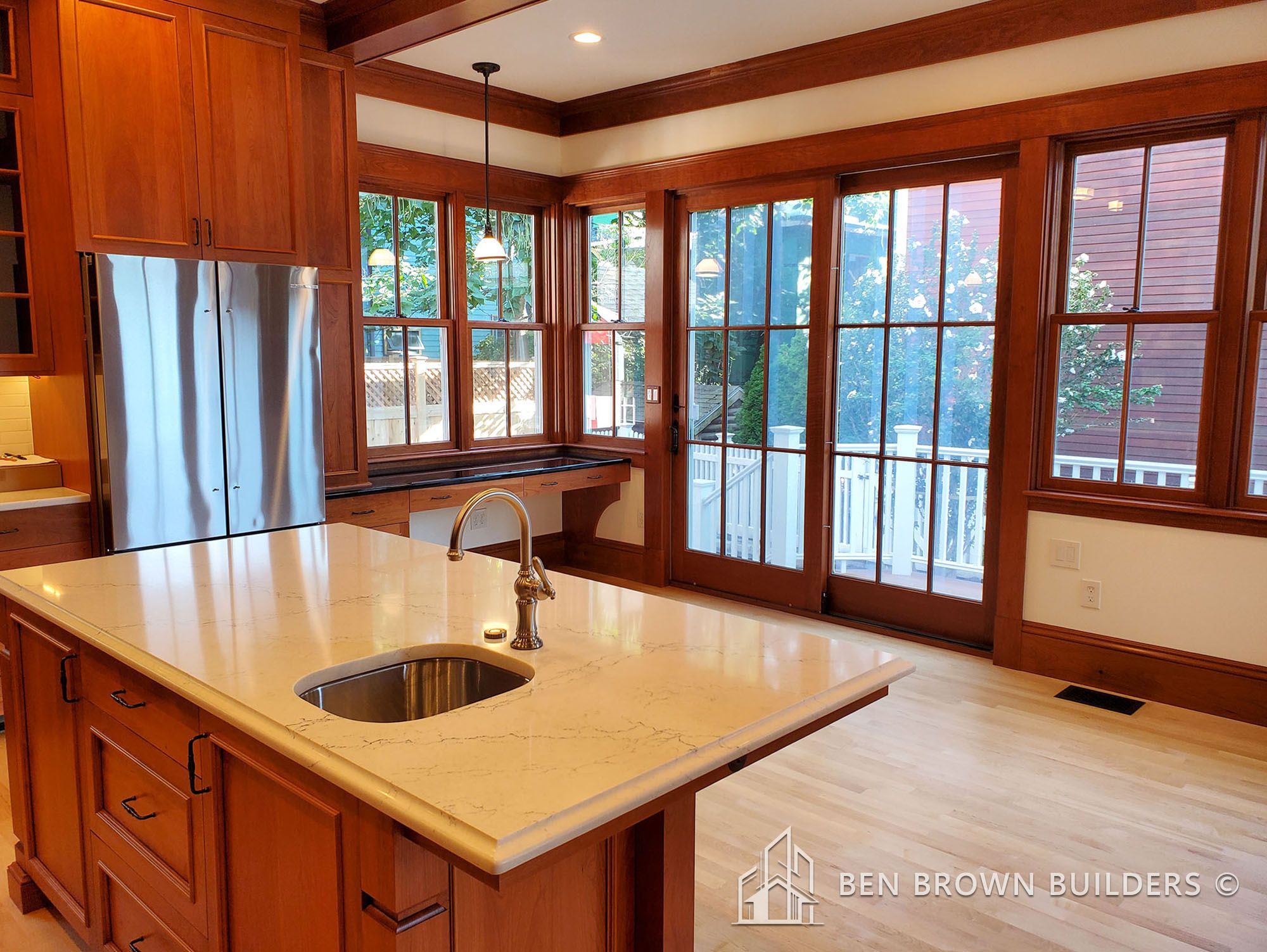 Elegant kitchen with wooden cabinets, marble countertops, and a view of the outdoors through large windows