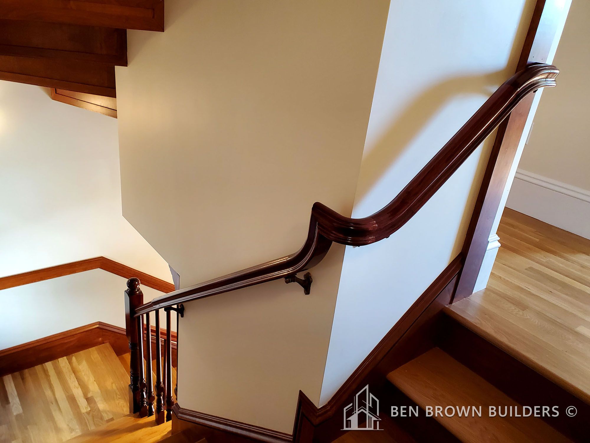Sophisticated wooden stairway with curved handrail and polished steps leading to a bright upper landing
