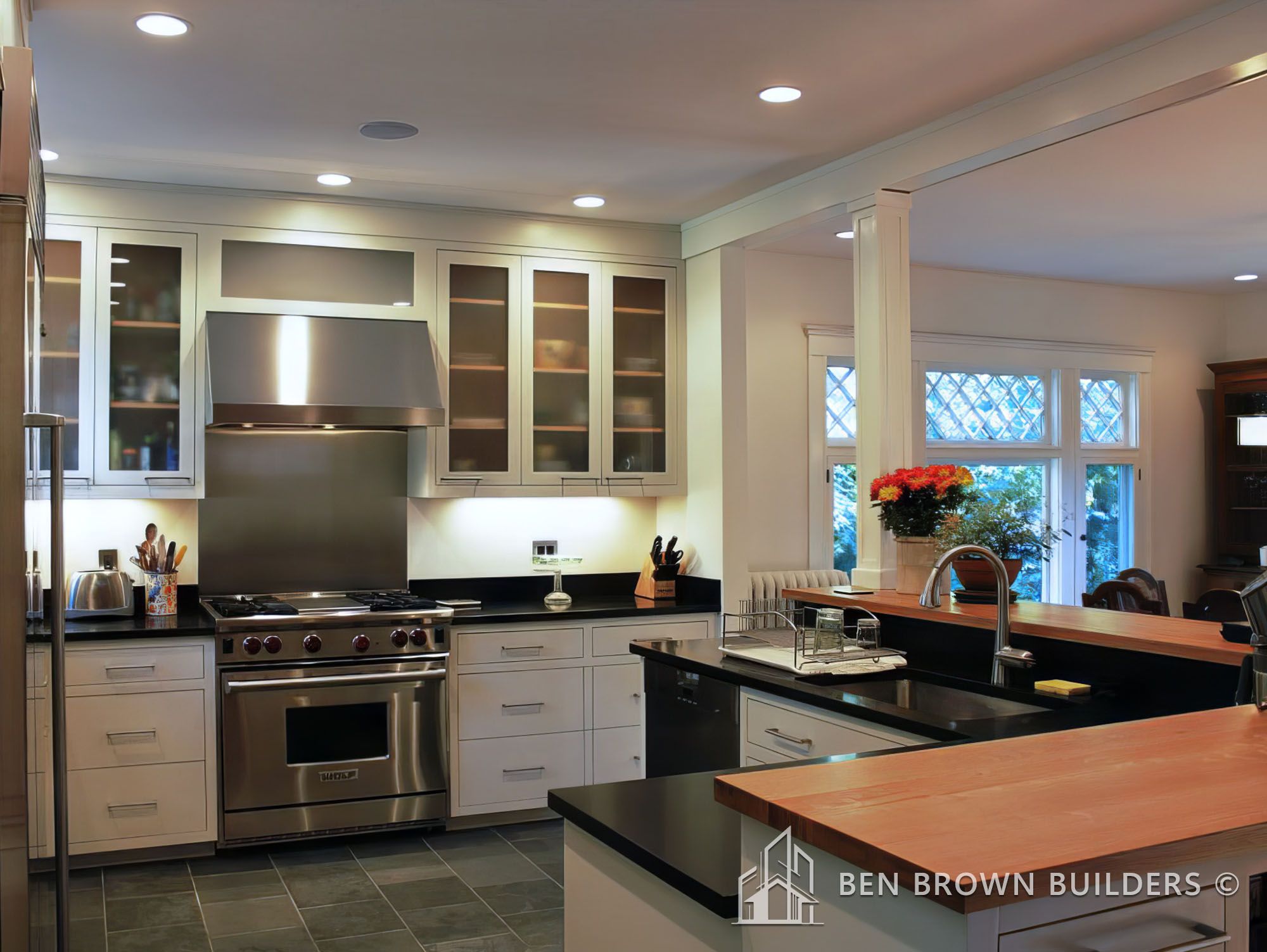 Sleek kitchen interior with stainless steel appliances, frosted glass cabinets, and a wooden countertop