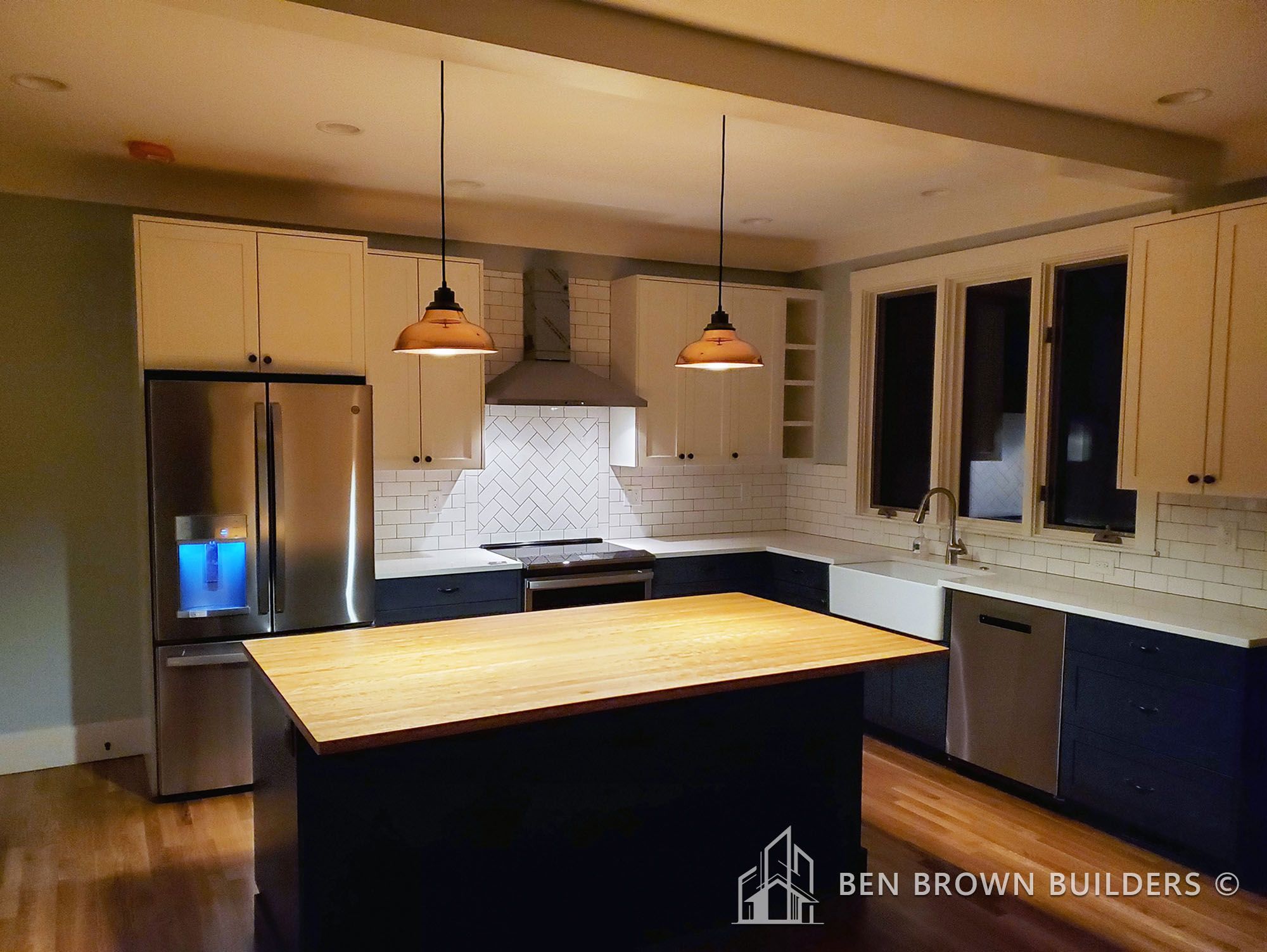 Modern kitchen with two-tone cabinets, stainless steel appliances, subway tile backsplash, and pendant lighting
