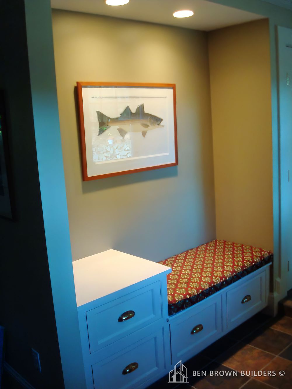 Cozy nook with a built-in bench, patterned cushion, framed artwork, and recessed lighting