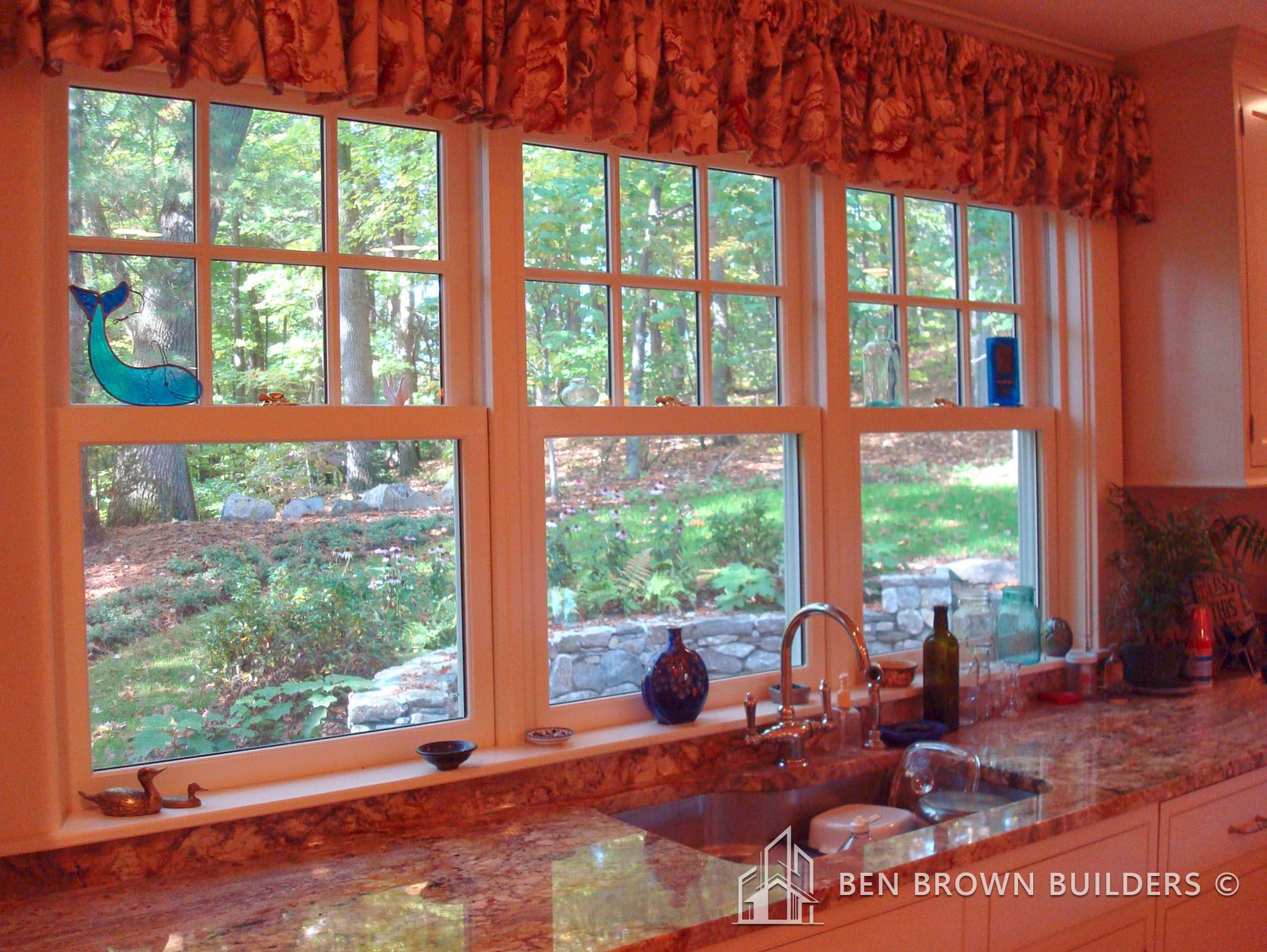 Spacious kitchen with cream cabinets, red backsplash, granite countertops, and pendant lights